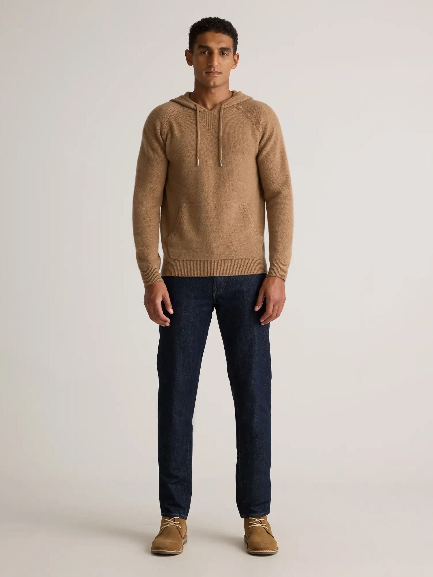 A model wearing a khaki-colored cashmere hoodie from Quince.
