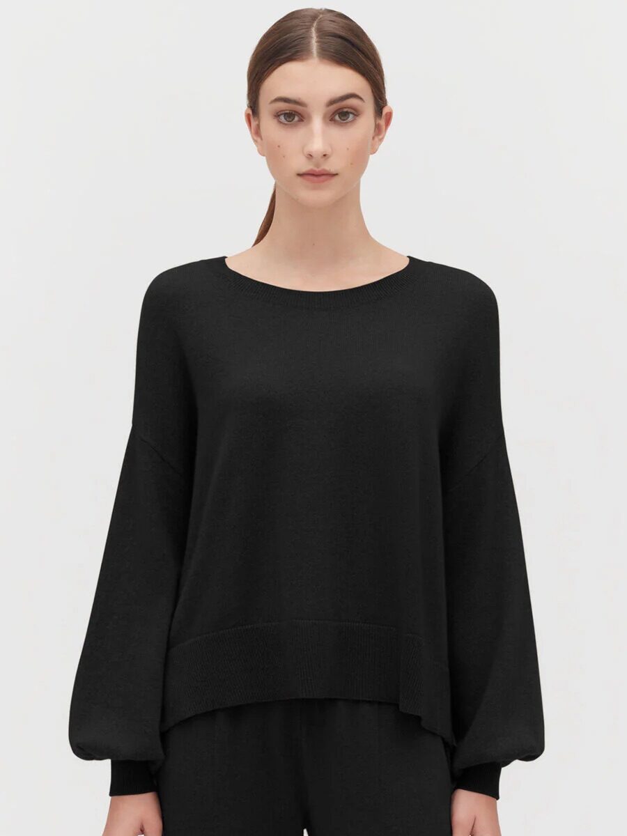 A model wearing a black balloon-sleeve cashmere sweater from Cuyana.