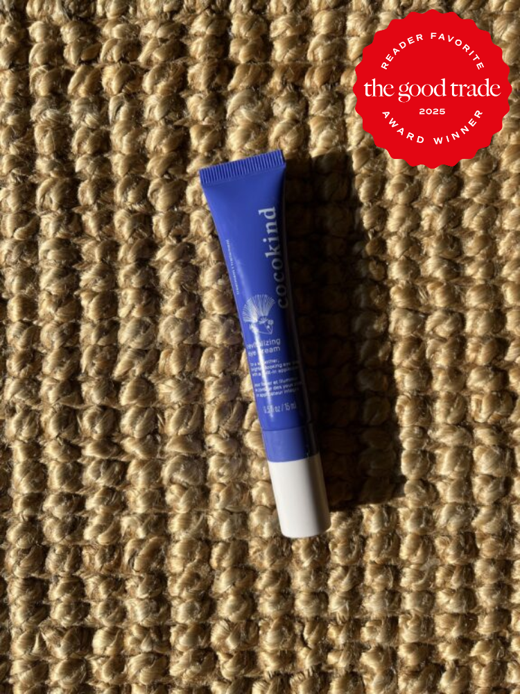 A tube of Cocokind product on a woven surface, featuring a red award sticker in the top right corner labeled "Reader Favorite The Good Trade 2025 Award Winner.