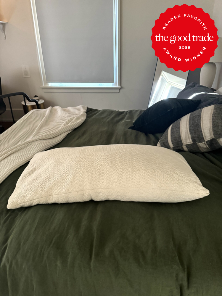 Bedroom with a bed featuring a green comforter, white pillow, and striped throw. A window in the background; award badge in the top corner.